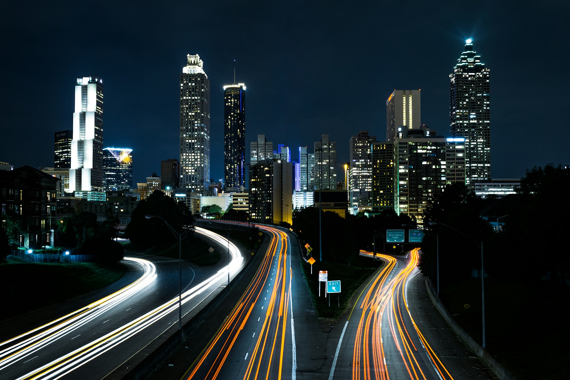 City skyline at night with light trails along the highways